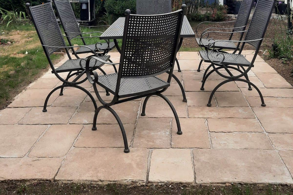how to build a paver patio - chalkingupsucccess.com Black metal garden chairs and table on a DIY paver patio