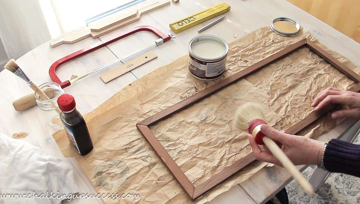 Applying white wax to a wood frame with a wax brush.