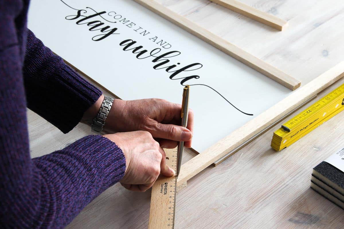 Pencilling in a 45° angle on a wooden frame as a guide for sawing.