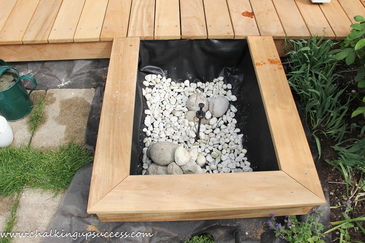 DIY above-ground-pond from ChalkingUpSuccess.com A layer of small and large stones at the bottom of the pond.
