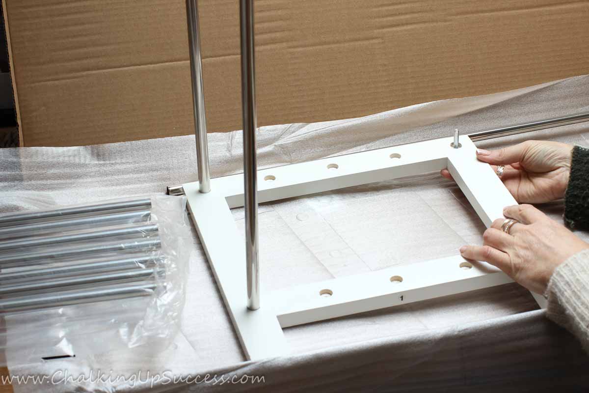 A lady showing how to assemble the corner bars of a closet floor shoe rack.
