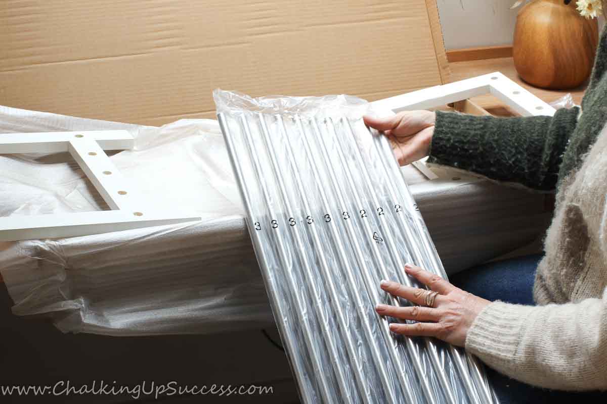 A lady showing two types of bars needed to build a closet floor shoe rack.