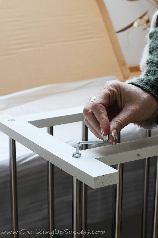A lady using a hex key to drive in screws on a closet floor shoe rack.
