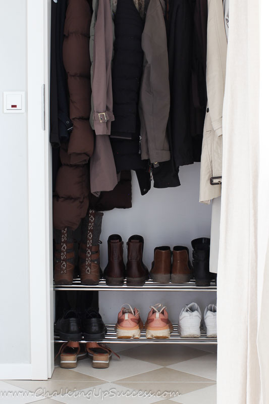 A small hallway closet looks tidy after organizing with a closet floor shoe rack.